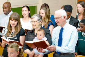 A diverse group of congregation members are singing together during church service.