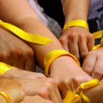 Hands bound by ribbon to show people working together in support